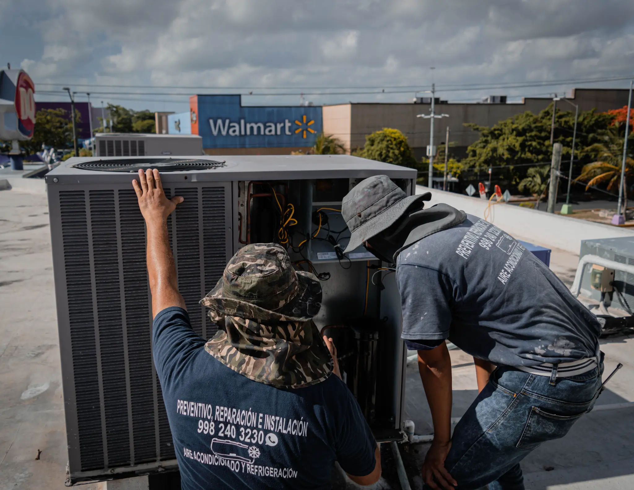 Two HVAC technicians inspecting a large rooftop cooling unit